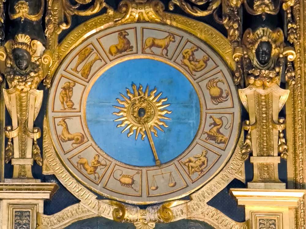 Quadrante zodiacale con dodici riquadri dorati e un sole con volto umano al centro
